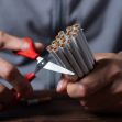 A person using scissors to cut a bundle of cigarettes. A person using scissors to cut a bundle of cigarettes.