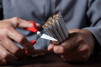 A person using scissors to cut a bundle of cigarettes.