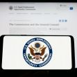 A hand holding a smartphone displaying the U.S. Equal Employment Opportunity Commission (EEOC) logo, with the agency's official website visible in the background. A hand holding a smartphone displaying the U.S. Equal Employment Opportunity Commission (EEOC) logo, with the agency's official website visible in the background.