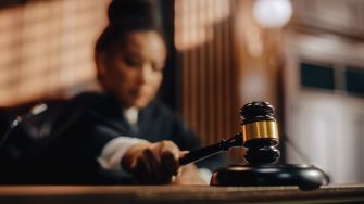 A blurred image of a judge holding a gavel in a courtroom setting.