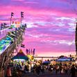 Carnival scene at sunset featuring a slide, Ferris wheel, and festival-goers. Carnival scene at sunset featuring a slide, Ferris wheel, and festival-goers.