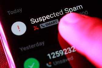 A finger pressing a smartphone screen displaying a "Suspected Spam" notification on an incoming call.