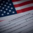 A close-up of a U.S. birth certificate displayed alongside the American flag. A close-up of a U.S. birth certificate displayed alongside the American flag.