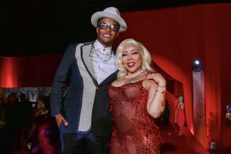 T.I. and Tiny Harris posing together at an event, dressed in stylish attire against a vibrant background.