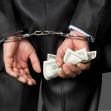 A businessman in a suit is handcuffed while holding cash, symbolizing fraud and legal consequences. A businessman in a suit is handcuffed while holding cash, symbolizing fraud and legal consequences.