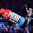 Logan Paul performing with a large promotional display of Prime Hydration drink at a wrestling event. Logan Paul performing with a large promotional display of Prime Hydration drink at a wrestling event.