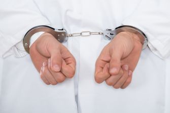 Hands in handcuffs, symbolizing legal consequences related to fraud.
