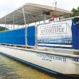 A boat named Chota Princess II with a banner for Chattahoochee Riverkeeper, near the water. A boat named Chota Princess II with a banner for Chattahoochee Riverkeeper, near the water.