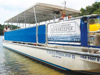 A boat named Chota Princess II with a banner for Chattahoochee Riverkeeper, near the water.