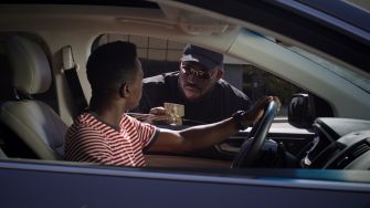 A police officer interacts with a driver during a traffic stop, with the driver holding a piece of identification.