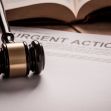 Image of a gavel resting on a sheet of paper labeled "URGENT ACTION," with a law book in the background. Image of a gavel resting on a sheet of paper labeled "URGENT ACTION," with a law book in the background.