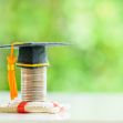 A graduation cap placed on a stack of coins, symbolizing the financial implications of college tuition and the impact of COVID-19 on educational expenses. A graduation cap placed on a stack of coins, symbolizing the financial implications of college tuition and the impact of COVID-19 on educational expenses.