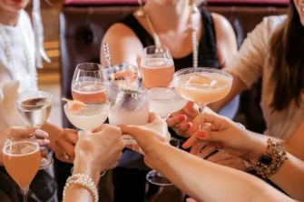 A group of women toasting with cocktails at a restaurant, highlighting social gatherings and promotions.