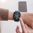 A person using an Apple iWatch, displaying various app icons on the screen. A person using an Apple iWatch, displaying various app icons on the screen.