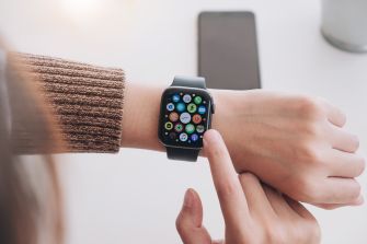 A person using an Apple iWatch, displaying various app icons on the screen.