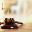Gavel and scales of justice on a wooden table, symbolizing a courtroom decision. Gavel and scales of justice on a wooden table, symbolizing a courtroom decision.