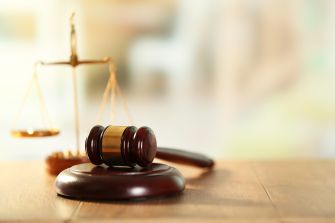 Gavel and scales of justice on a wooden table, symbolizing a courtroom decision.