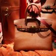 A brown Hermès Birkin handbag displayed with other luxury items. A brown Hermès Birkin handbag displayed with other luxury items.