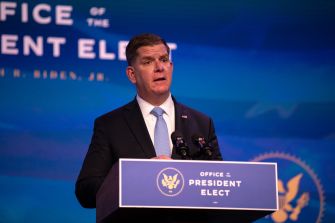 A man speaking at a podium with the seal of the Office of the President Elect in the background.