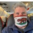 A man wearing a California flag face mask while seated on an airplane. A man wearing a California flag face mask while seated on an airplane.