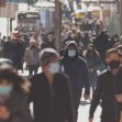 Crowd of people walking street wearing masks