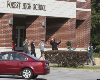 Students exit Forest High School with their hands raised in a precautionary response following a shooting incident.
