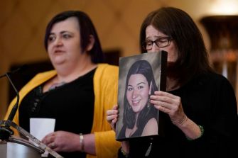 A woman holding a framed photo of a victim speaks during a press conference about the historic $73 million settlement with gun maker Remington.