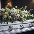 A silver casket adorned with flowers in a somber setting. A silver casket adorned with flowers in a somber setting.