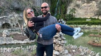 A couple poses together outdoors with a scenic backdrop, smiling and enjoying their time together.