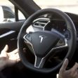Image of a Tesla steering wheel and dashboard, illustrating the vehicle's interior with driver hands potentially engaged in controlling the car. Image of a Tesla steering wheel and dashboard, illustrating the vehicle's interior with driver hands potentially engaged in controlling the car.