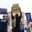 Protesters hold signs advocating for student debt cancellation outside the Supreme Court building. Protesters hold signs advocating for student debt cancellation outside the Supreme Court building.