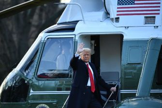 Former President Donald Trump waving as he exits a helicopter.