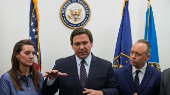A press conference featuring Florida Governor Ron DeSantis speaking about cruise ship regulations, surrounded by officials.