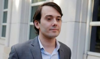 A young man in a suit walking outside a building, possibly in a legal context.