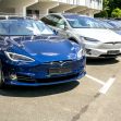 A row of Tesla electric vehicles parked in a lot, including a blue Tesla Model S and a silver Tesla Model X. A row of Tesla electric vehicles parked in a lot, including a blue Tesla Model S and a silver Tesla Model X.