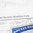 Social Security disability form with a Social Security card in the foreground. Social Security disability form with a Social Security card in the foreground.