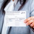 A person holding a COVID-19 vaccination record card, displaying vaccination details. A person holding a COVID-19 vaccination record card, displaying vaccination details.