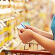 A person holding discount coupons while shopping in a grocery store aisle. A person holding discount coupons while shopping in a grocery store aisle.
