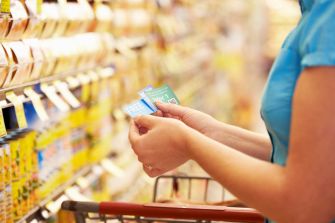 A person holding discount coupons while shopping in a grocery store aisle.
