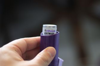 A hand holding an Advair Diskus inhaler, a medication used for asthma.