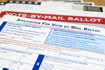 Mail-in ballot applications on a table, highlighting the voting process for upcoming elections.
