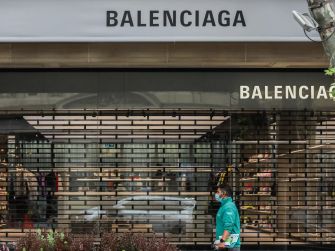 A person walks past a Balenciaga store closed with metal grilles, reflecting the brand's current controversies.