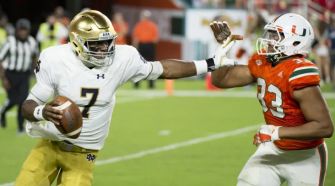A college football player evading a tackle during a game, illustrating the competitive nature of college athletics.