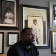 A man seated in an office surrounded by framed artwork and photographs, reflecting on his experiences related to a wrongful arrest. A man seated in an office surrounded by framed artwork and photographs, reflecting on his experiences related to a wrongful arrest.