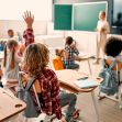 A classroom scene with students raising their hands while a teacher addresses the class. A classroom scene with students raising their hands while a teacher addresses the class.