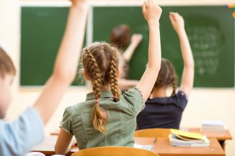 Students raising their hands in a classroom setting.
