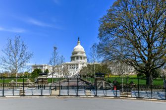 U.S. Capitol building surrounded by security fencing on a clear day.