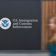 Sign of U.S. Immigration and Customs Enforcement (ICE) with a blurred figure in the foreground. Sign of U.S. Immigration and Customs Enforcement (ICE) with a blurred figure in the foreground.