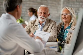 An older couple discussing healthcare options with a doctor in an office setting.