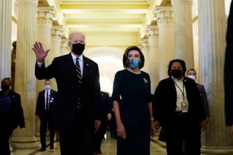President Biden and Speaker Nancy Pelosi walking through a corridor, both wearing masks.